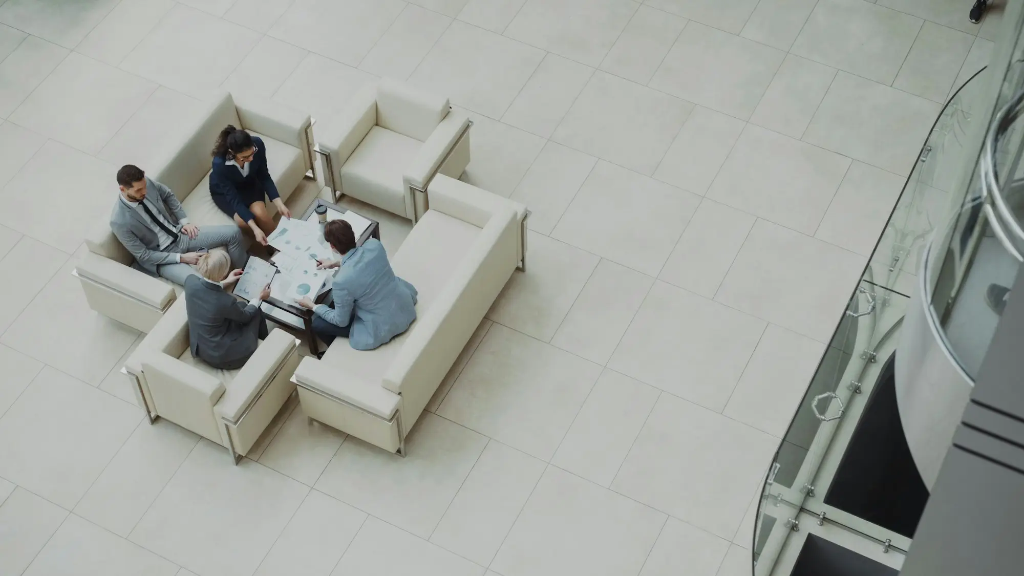 Overhead view of four business people meeting around a low table covered in papers, like directors and an administrator discussing a deed of company arrangement proposal