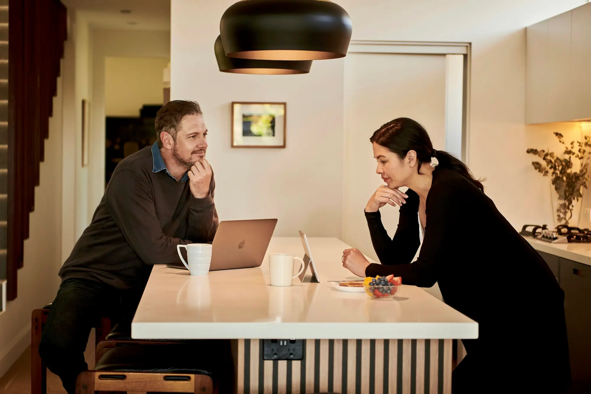 Two business owners at a kitchen bench with a laptop and tablet, weighing up how to handle a disputed tax bill