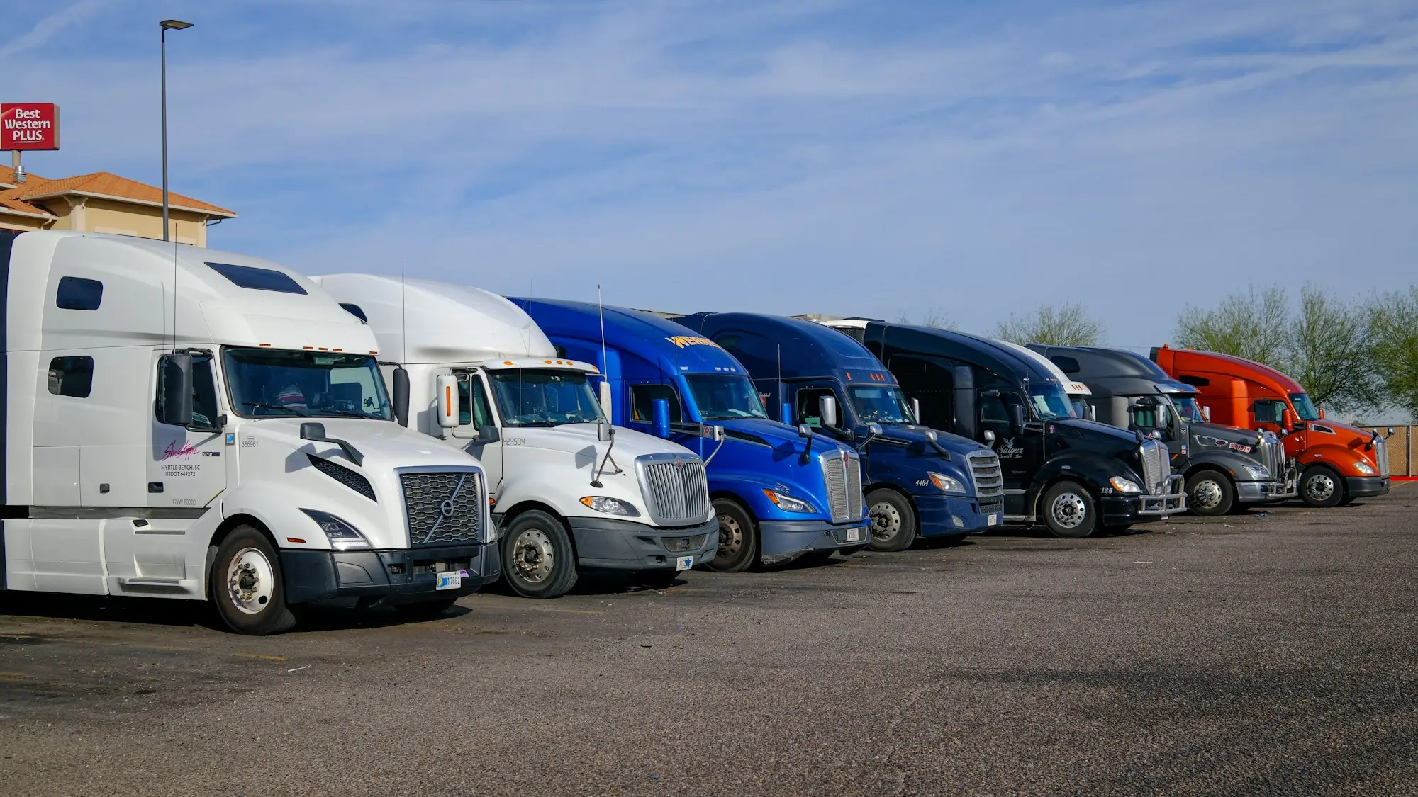 Several semi-trucks parked in a row at a transport yard